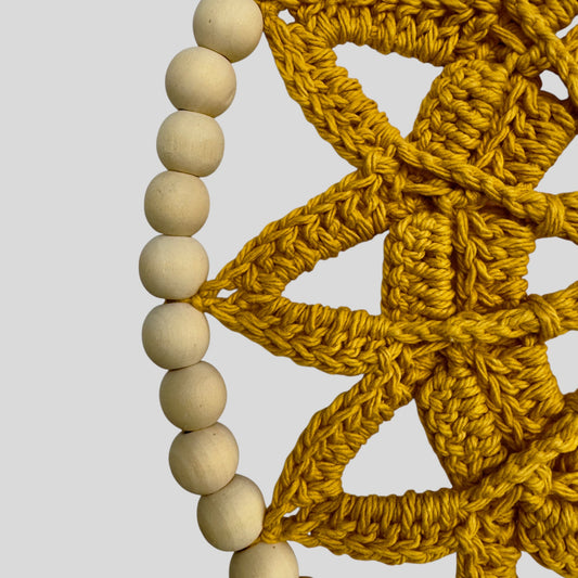 Yellow crocheted star with wooden beads on a gray background